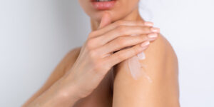 - Article Femme Actuelle, Aromathérapie « Non, le froid n’aura pas ma peau » - Close beauty portrait of topless woman with perfect skin holding bottle of shampoo, lotion, apply on shoulders and body, on white background